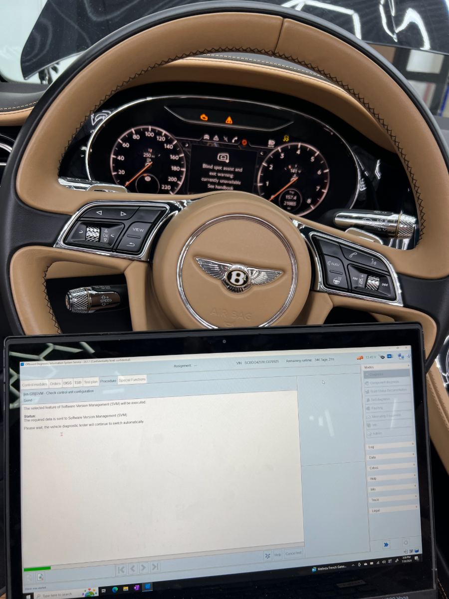 Bentley steering wheel and instrument cluster with ODIS Service running an SVM software version management procedure on a connected Lenovo Yoga