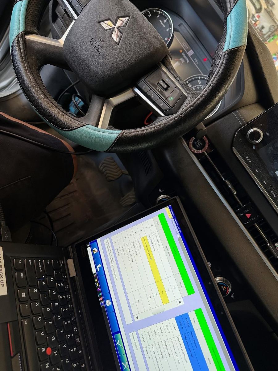 Mitsubishi steering wheel with diagnostic system scan running on a Lenovo ThinkPad showing module fault codes and pending DTCs